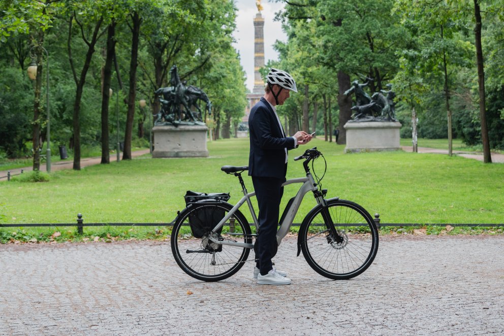 Mand står med elcykel og mobiltelefon